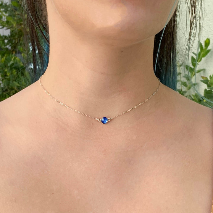 model wearing round blue childhood cancer necklace on sterling silver chain 